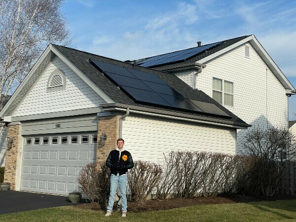 Tyler McDonough standing in front of a house with solar panels.